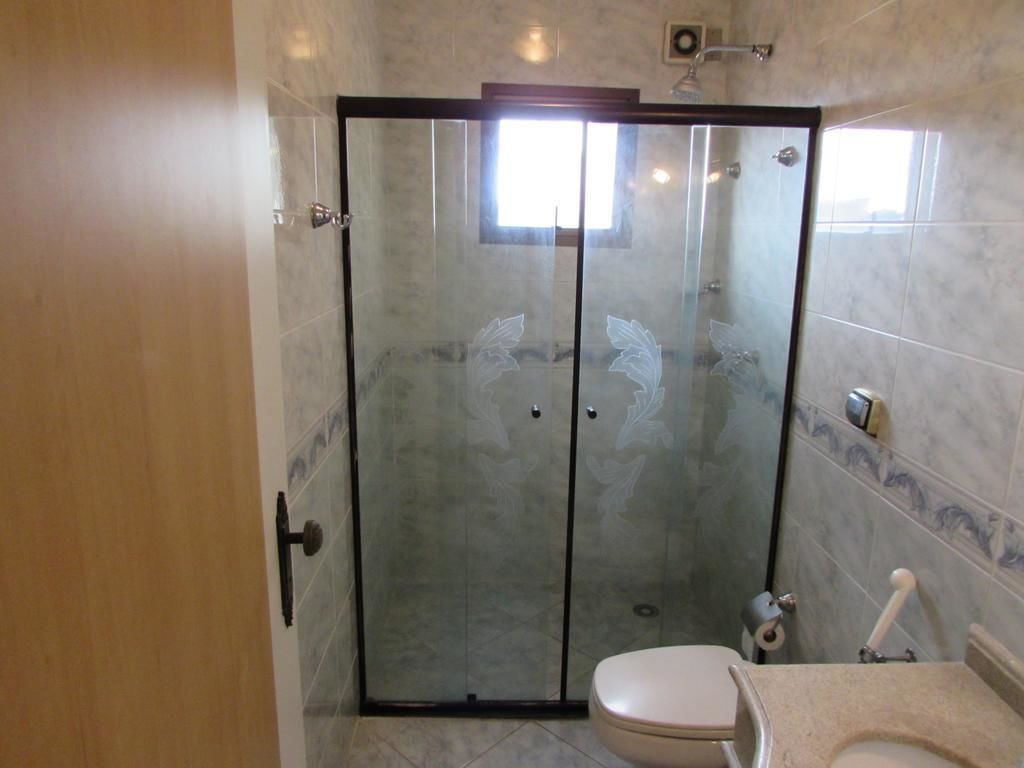 Un baño con ducha envuelta en vidrio, inodoro y lavamanos.