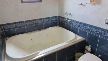 Une salle de bain avec une baignoire, des toilettes et une fenêtre.