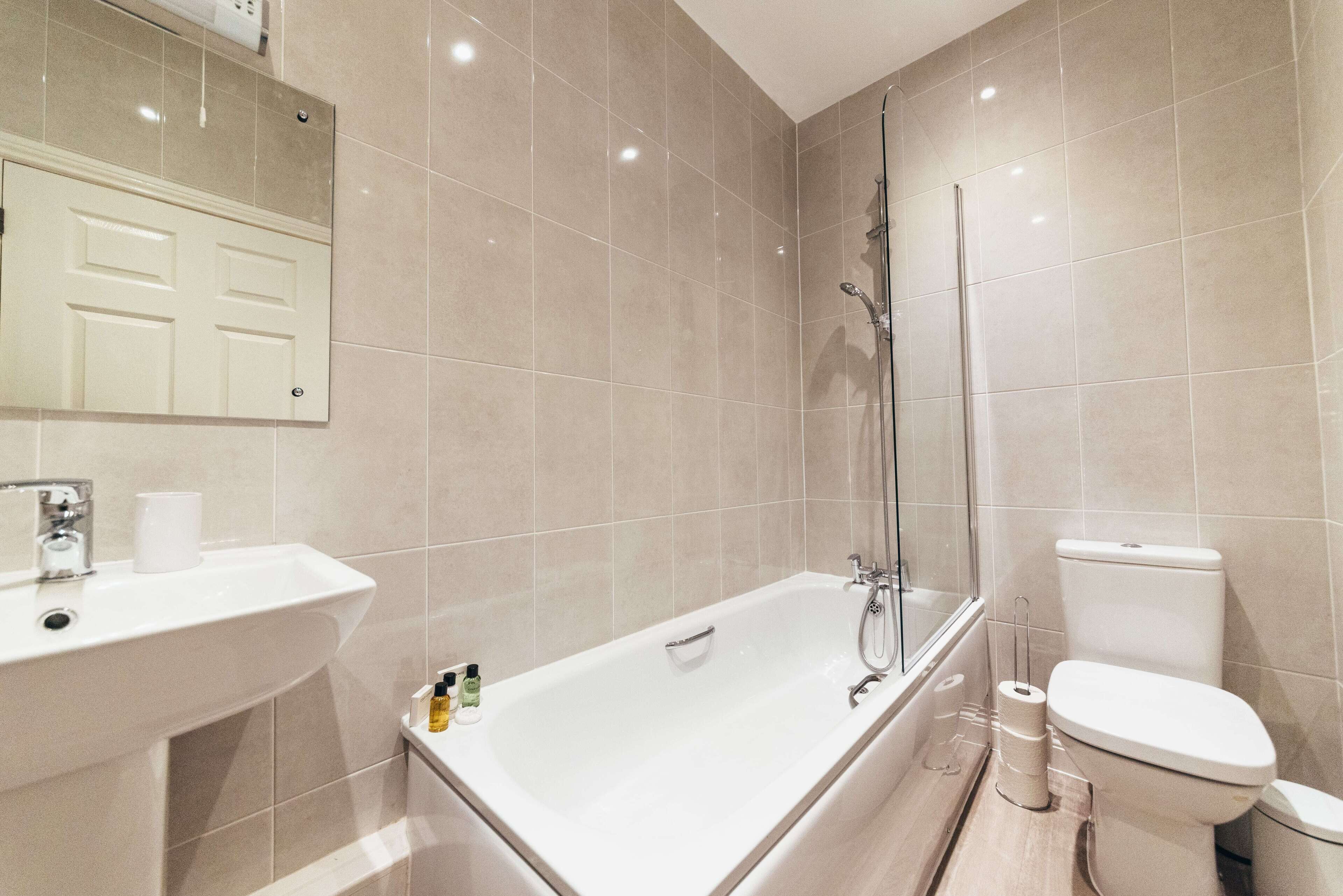 Une salle de bain équipée d’une baignoire, de toilettes, d’un lavabo et d’un miroir.