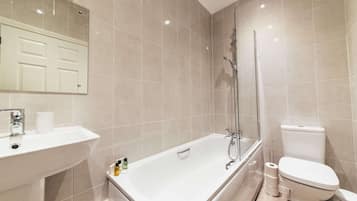 Une salle de bain équipée d’une baignoire, de toilettes, d’un lavabo et d’un miroir.