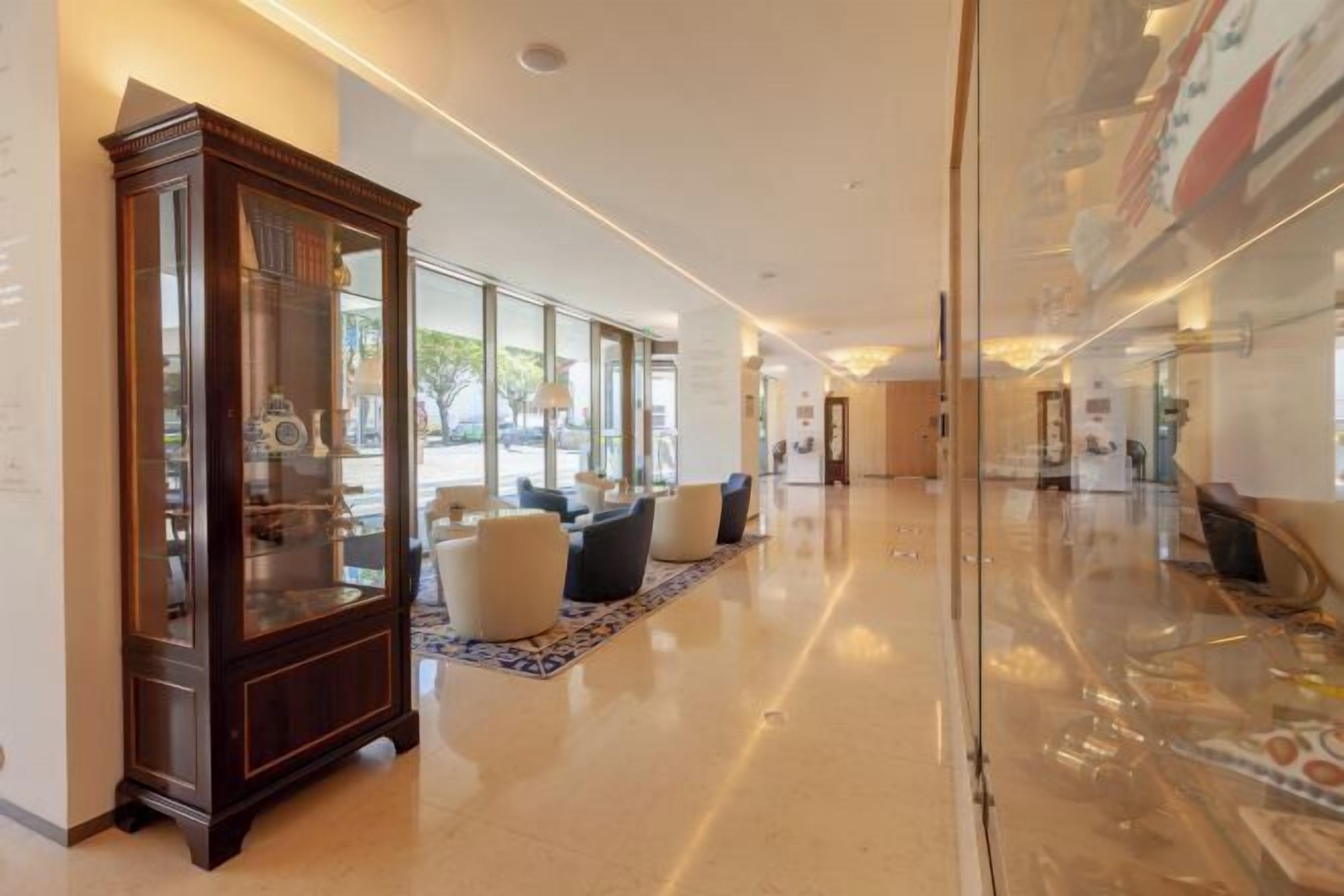 A spacious lobby with a large wooden cabinet, comfortable seating, and a glass partition.
