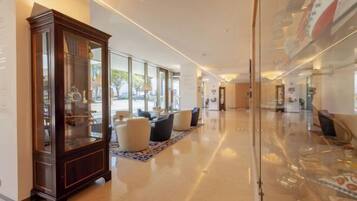 A spacious lobby with a large wooden cabinet, comfortable seating, and a glass partition.