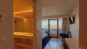 Une chambre d’hôtel avec un balcon, un lit, un bureau et une télévision.