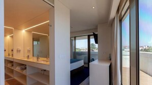 Une chambre d’hôtel moderne dotée d’une grande fenêtre, d’un lit, d’une coiffeuse intégrée et d’un balcon.
