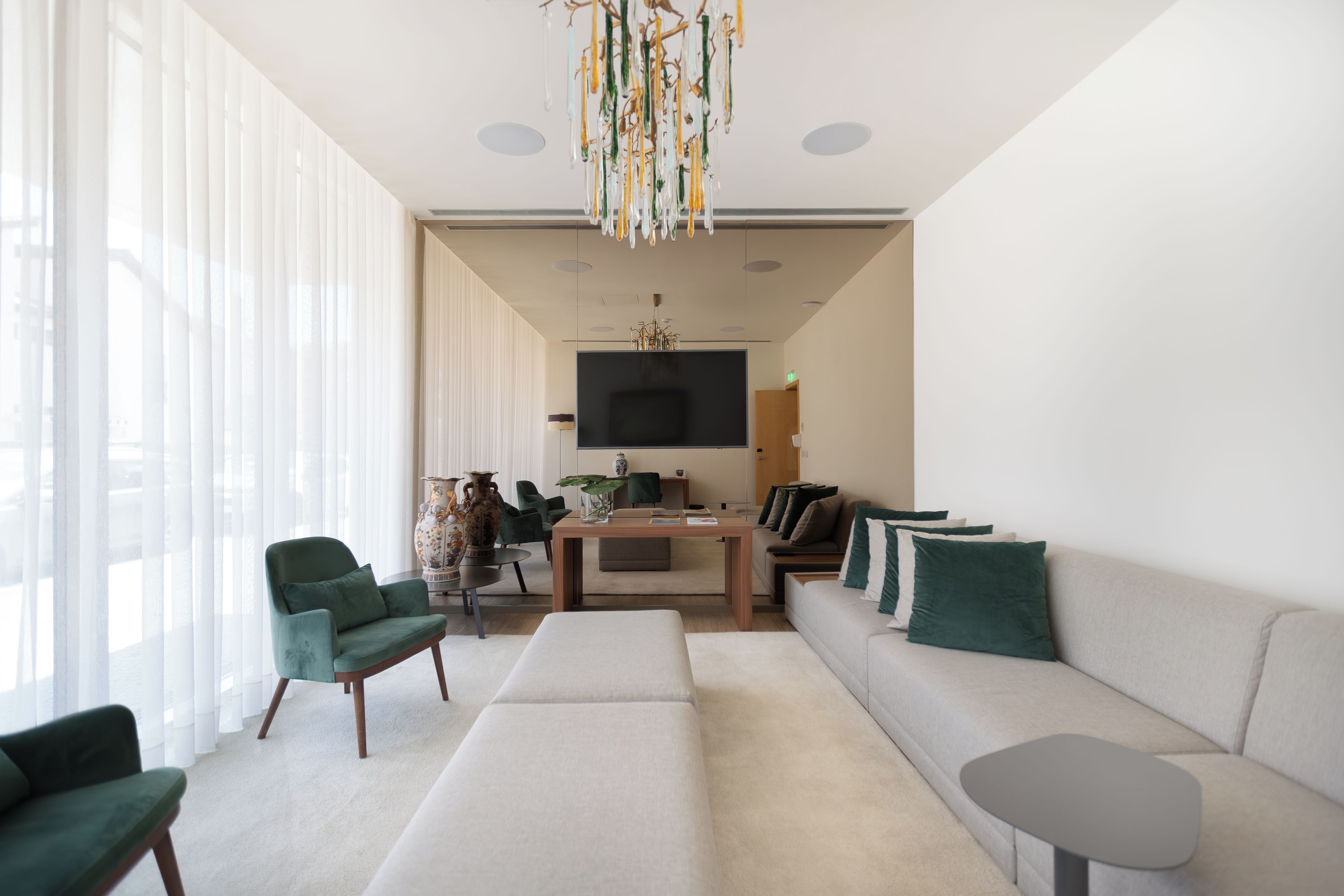 A modern living room with a sofa, chairs, a coffee table, and a TV.