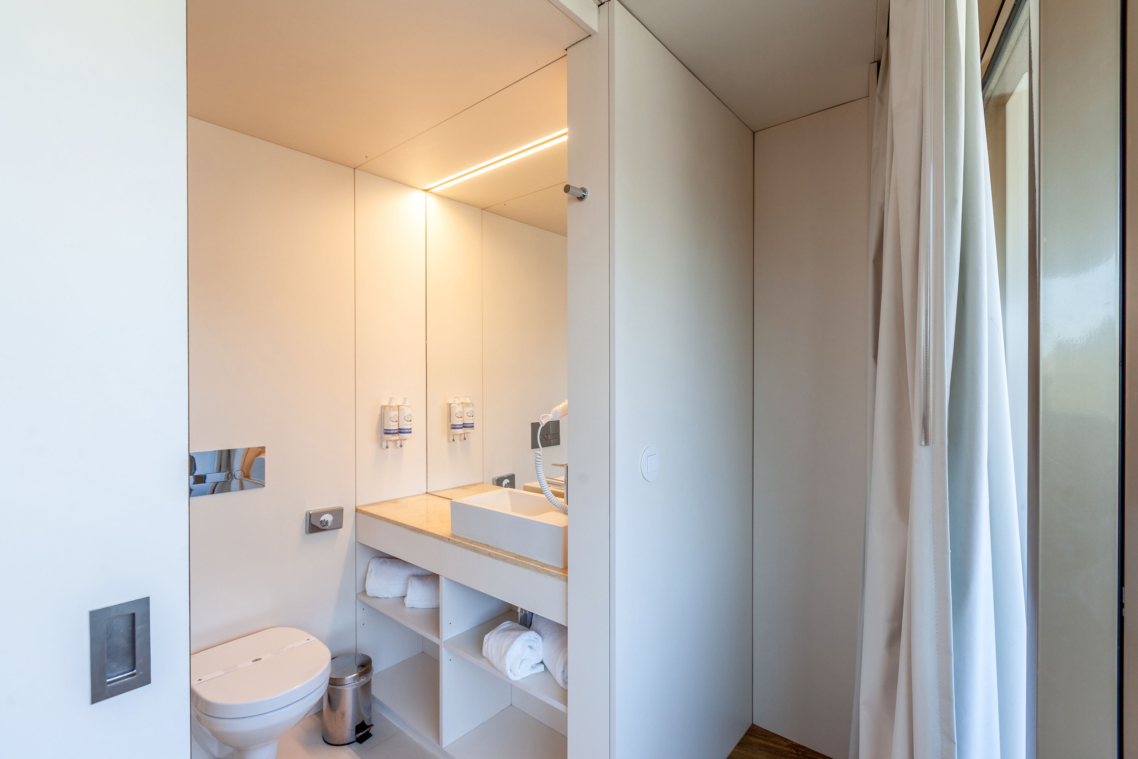A modern bathroom with a toilet, sink, and mirror.