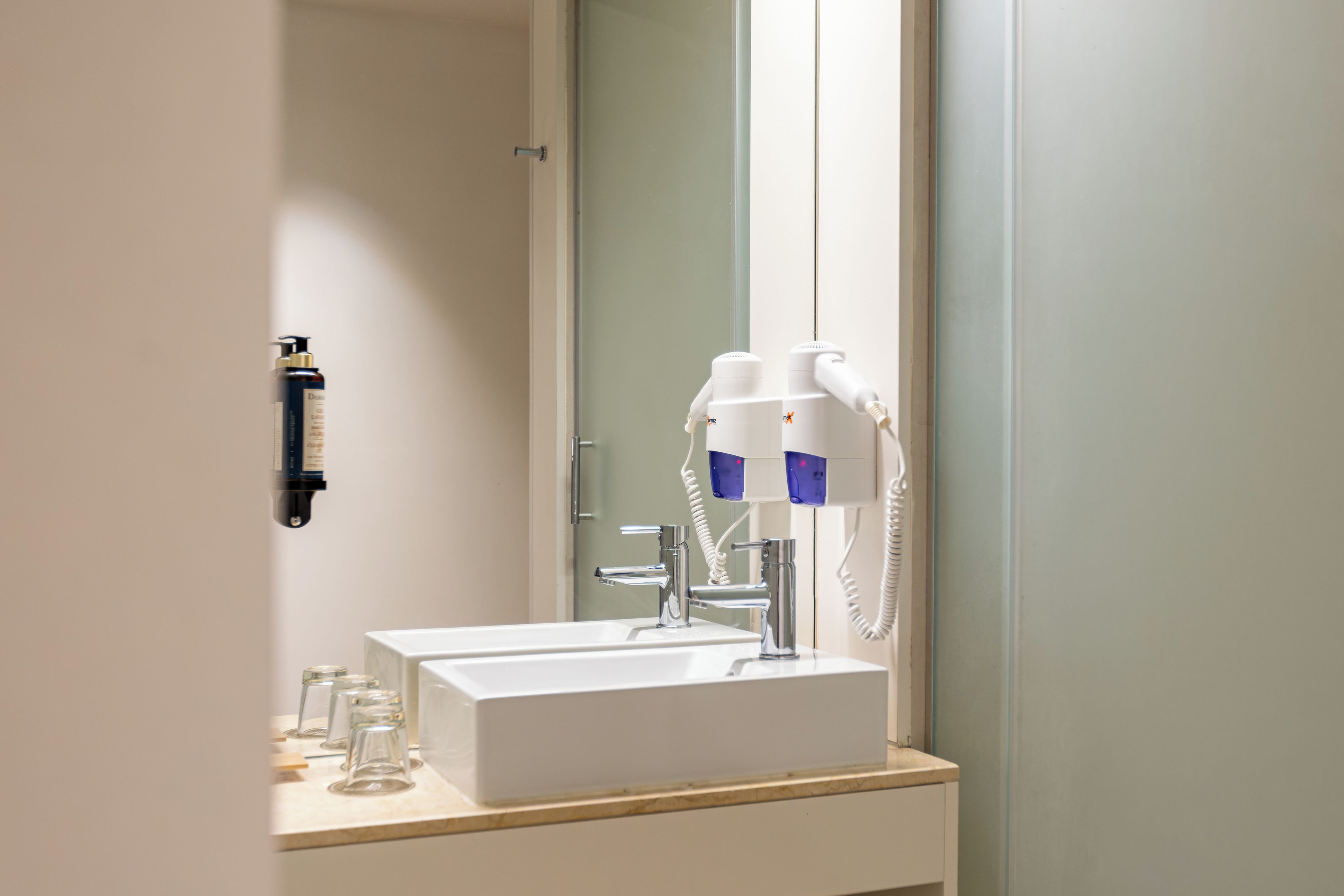 A bathroom with a white sink, a mirror, and a hairdryer.