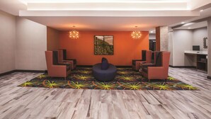 A modern lobby with a central seating area, a large wall art piece, and a patterned floor. - La Quinta Inn & Suites by Wyndham Baton Rouge - Port Allen (Port Allen)