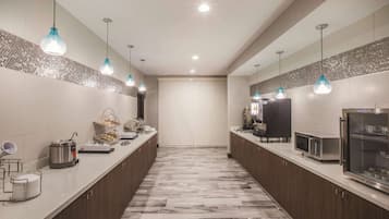A modern kitchen with marble flooring, stainless steel appliances, and pendant lighting.