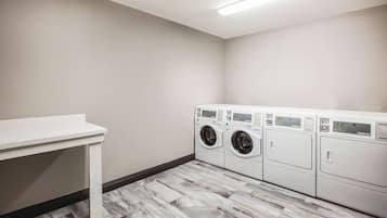 A laundry room with a white countertop and a row of stacked front-loading washers and dryers.