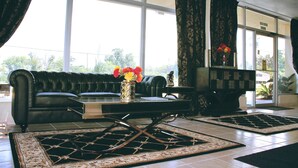 A living room with a leather sofa, a coffee table, and a vase with flowers. - Residence Hub Inn & Suites (Marianna)