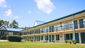 A two-story motel with a blue roof and a green lawn in front. - Residence Hub Inn & Suites (Marianna)