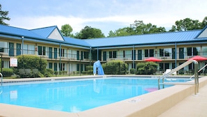 A swimming pool with a blue roof, surrounded by a fence and a building with multiple windows. - Residence Hub Inn & Suites (Marianna)