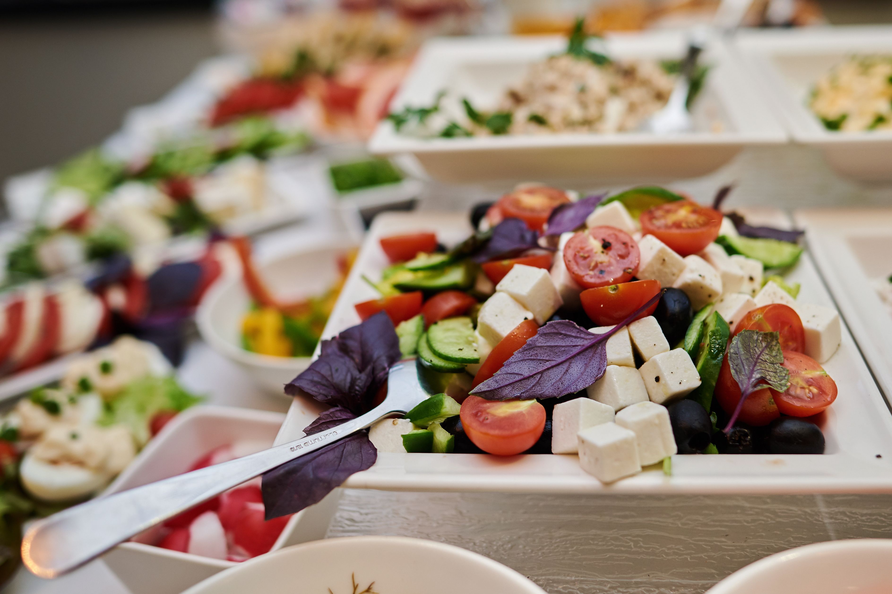 A variety of food platters with different salads and cheeses.