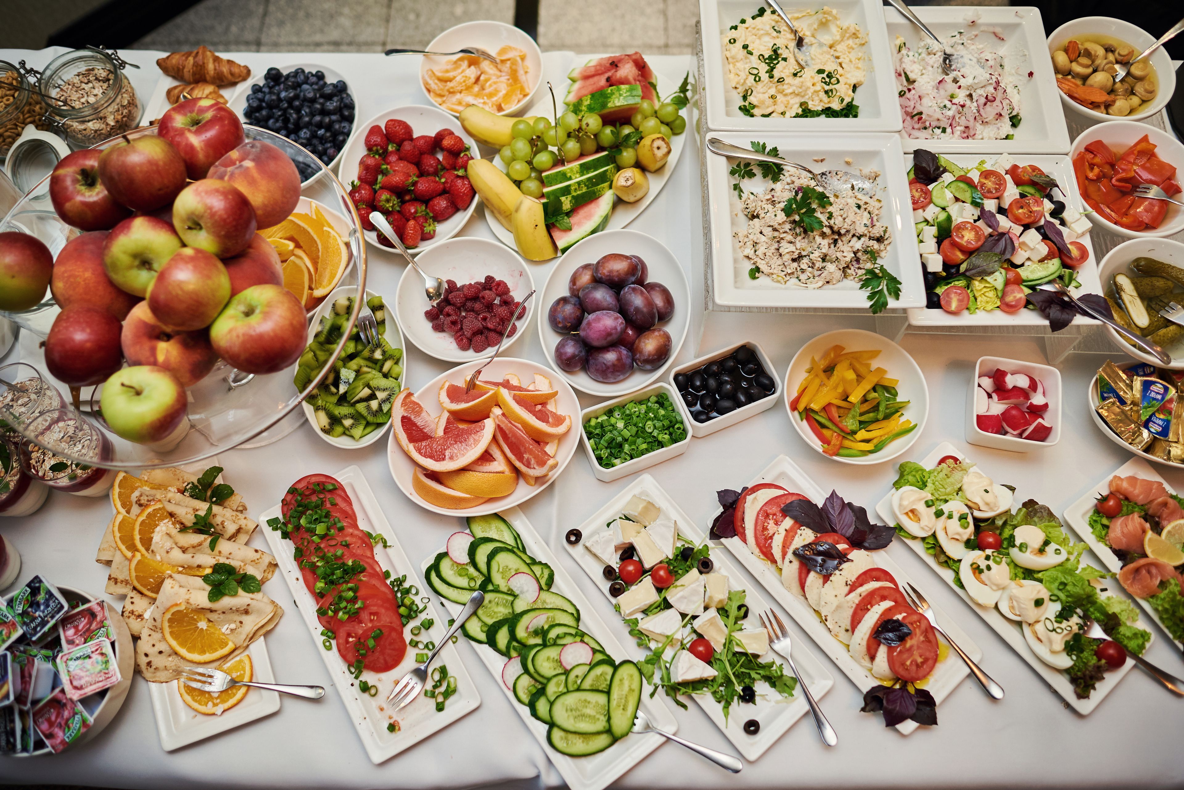A table with various fruits, vegetables, and cheeses.