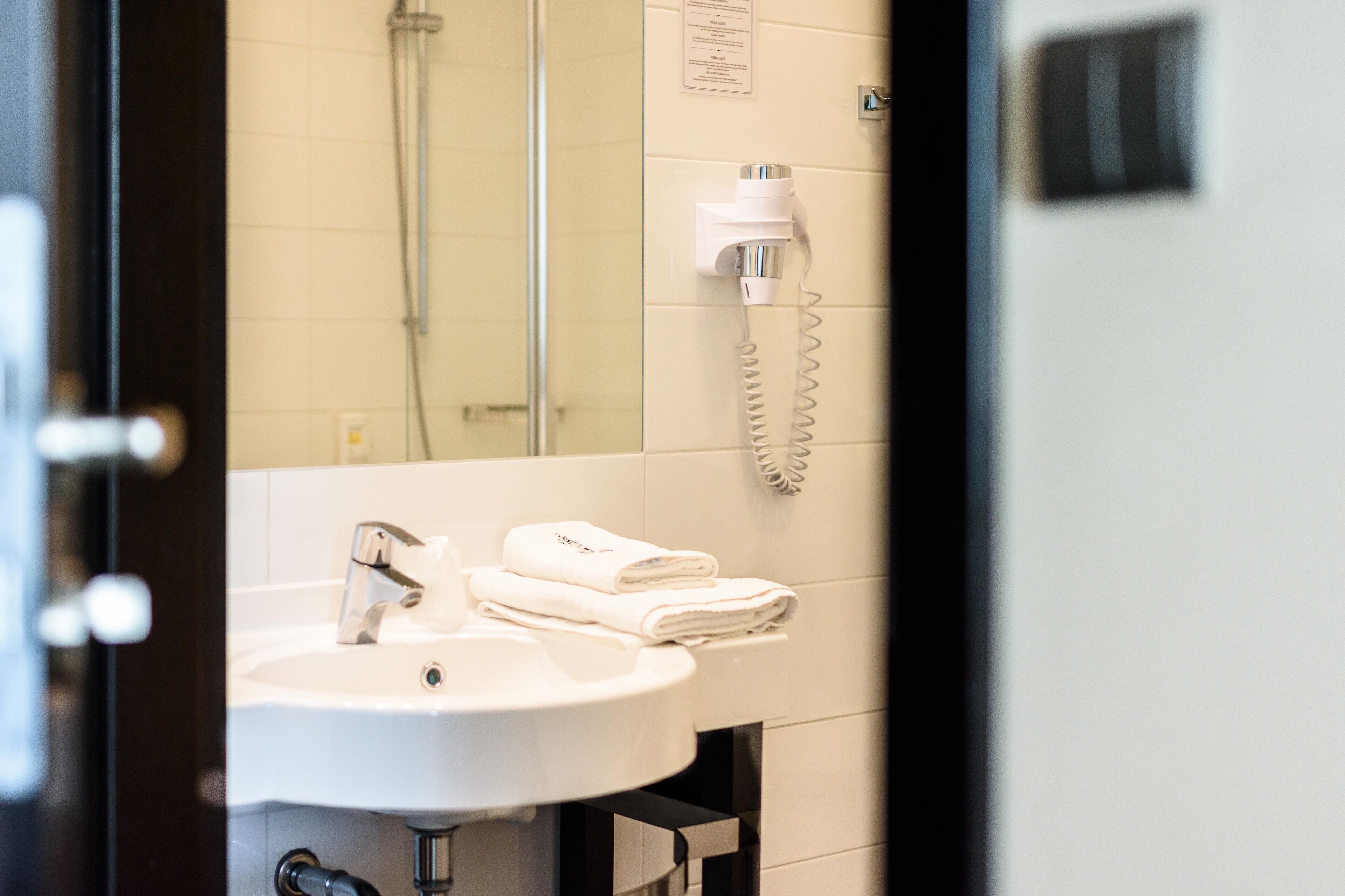 A bathroom with a sink, a towel rack, and a hairdryer mounted on the wall.