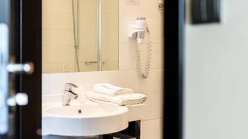 A bathroom with a sink, a towel rack, and a hairdryer mounted on the wall.