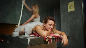 A person resting on a counter with a towel, another person in the background, and a sign on the wall.