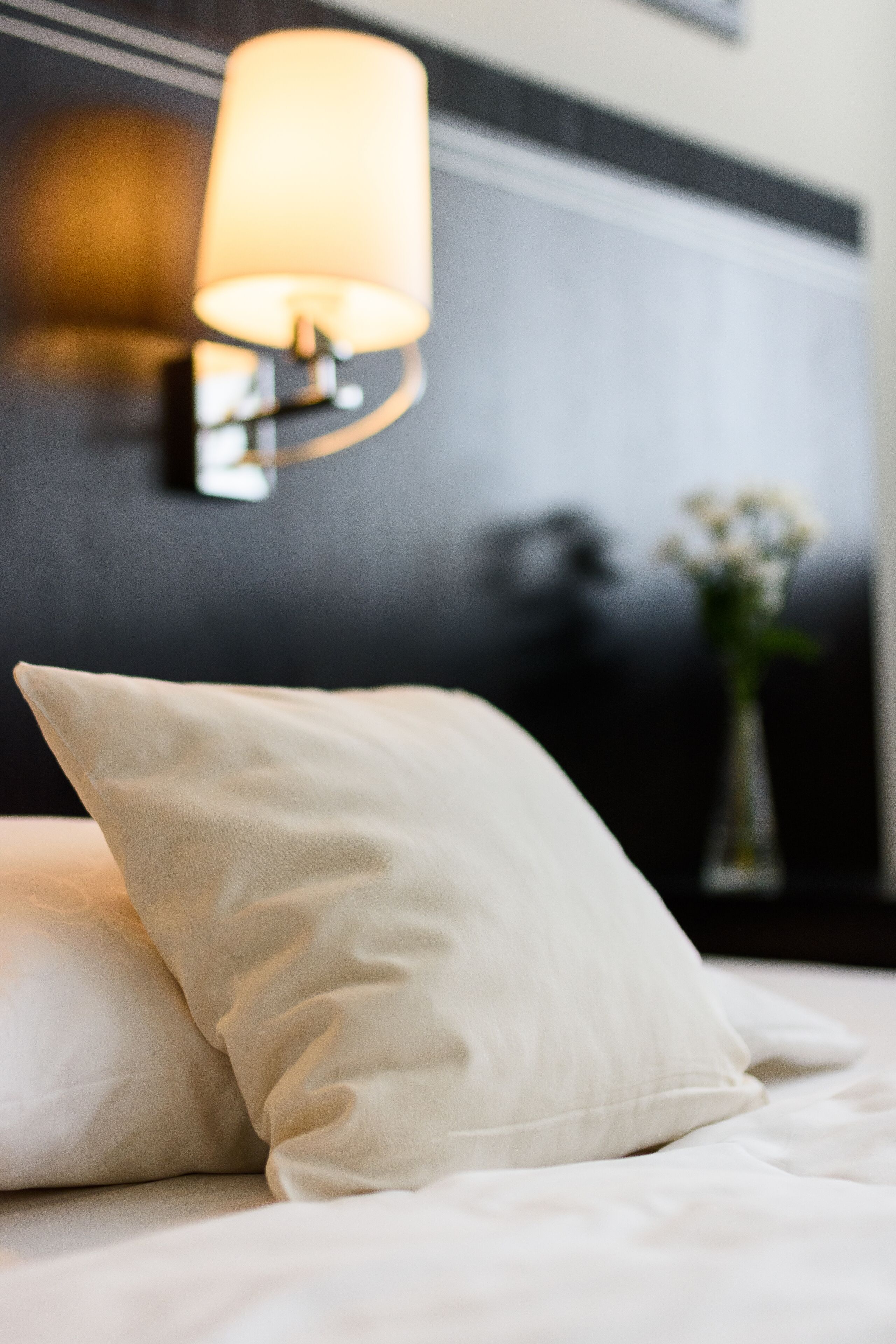 A bed with white bedding and a single white pillow.