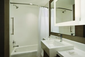 Une salle de bain moderne avec une baignoire, deux lavabos et un grand miroir.
