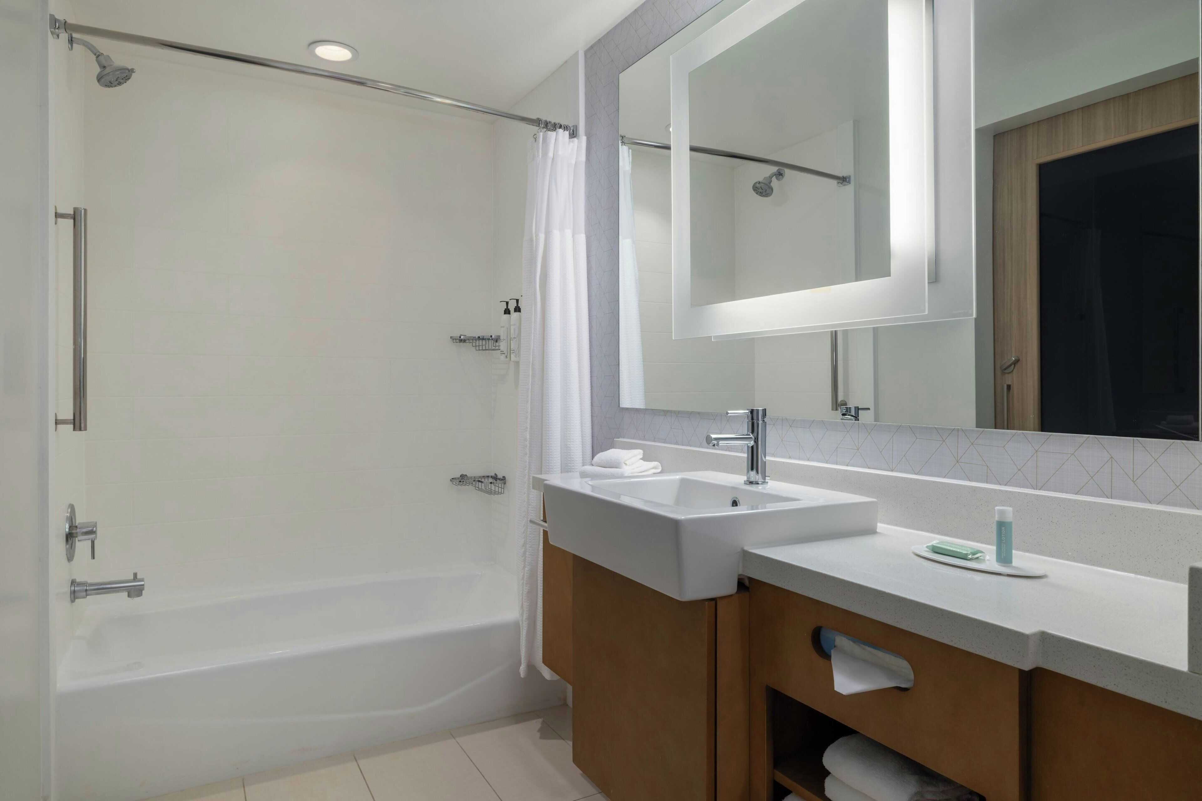 A modern bathroom with a walk-in shower, a large mirror, and a vanity with a sink.