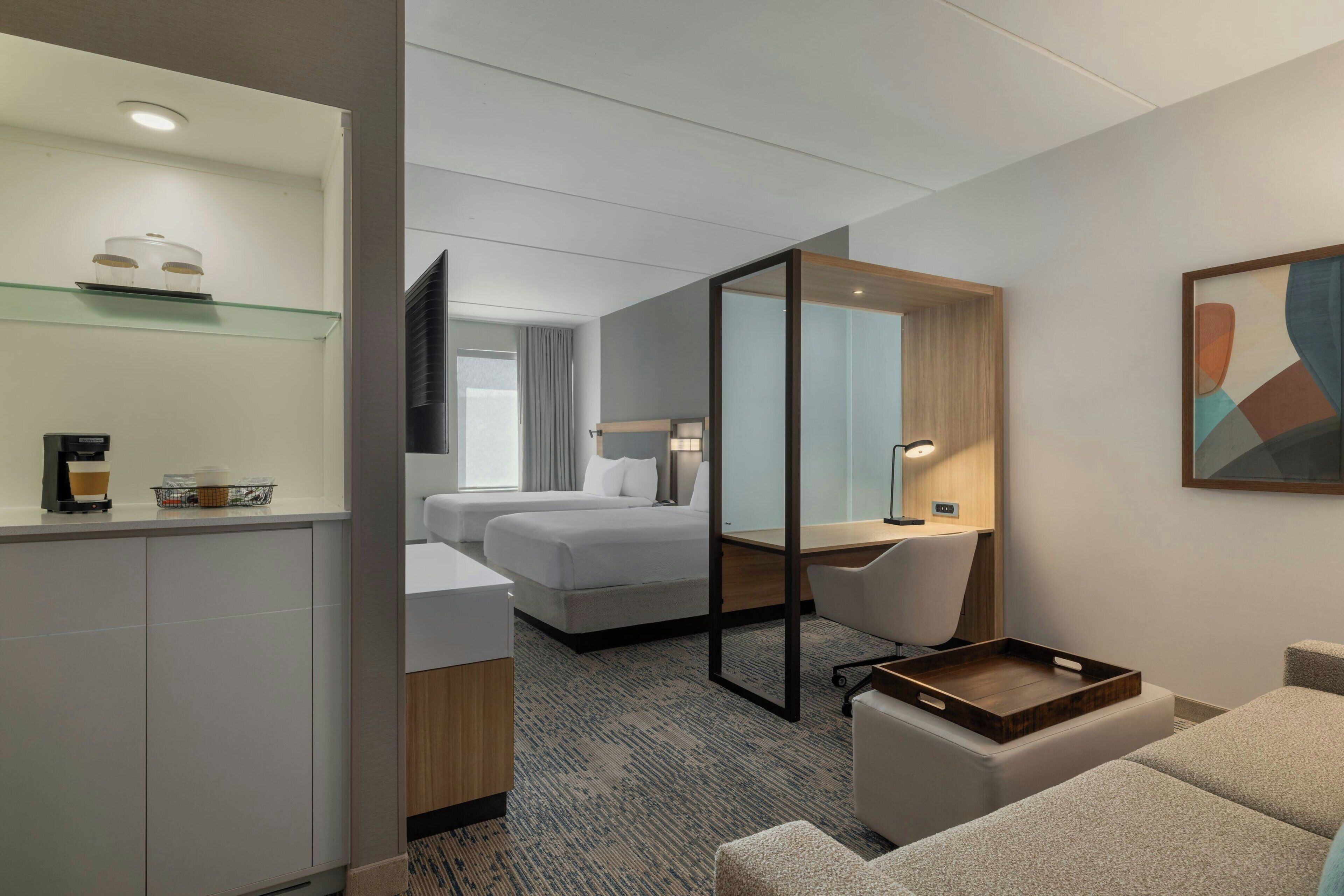 Een hotelkamer met een bed, een bureau, een stoel, een koffieapparaat en een televisie.