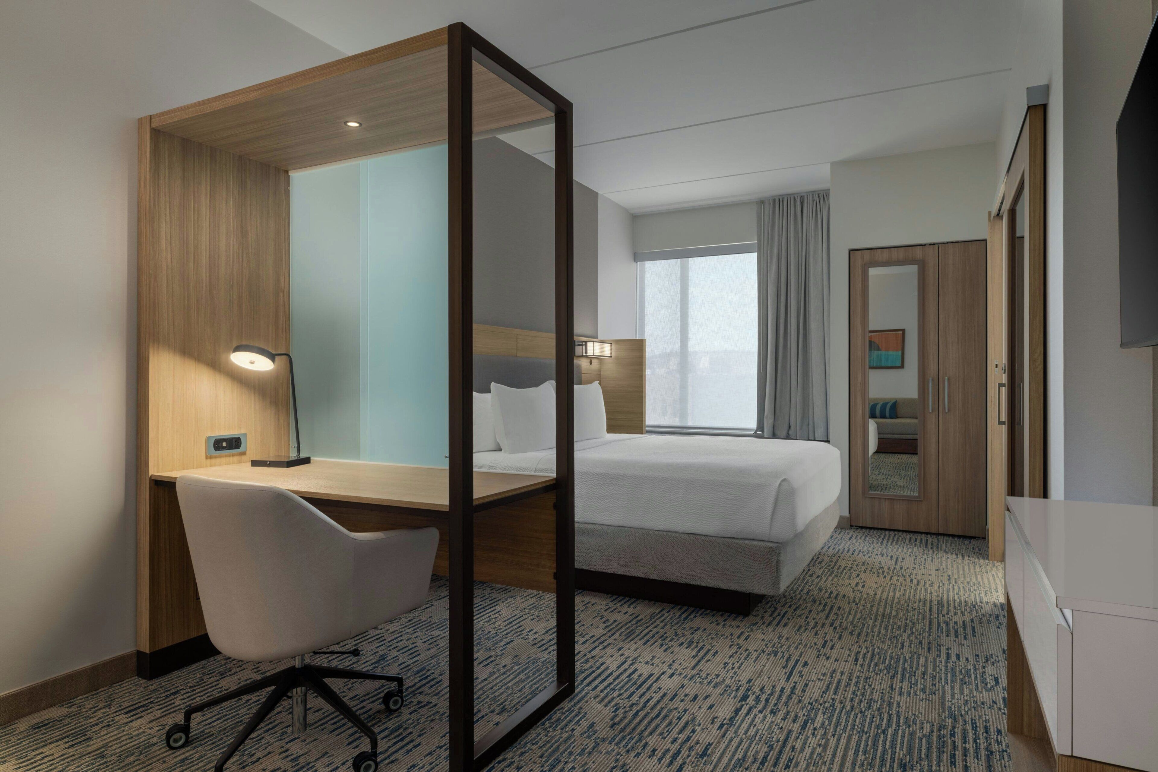 Ein Hotelzimmer mit Schreibtisch, Stuhl, Bett und Kleiderschrank.