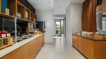 A modern kitchen with a long counter, various food dispensers, and a view to the outdoors.