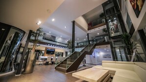 A spacious lobby with a staircase, seating area, and a large TV screen.
