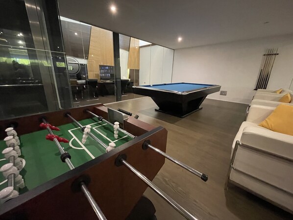 Una sala de estar moderna con mesa de fútbol y mesa de billar.