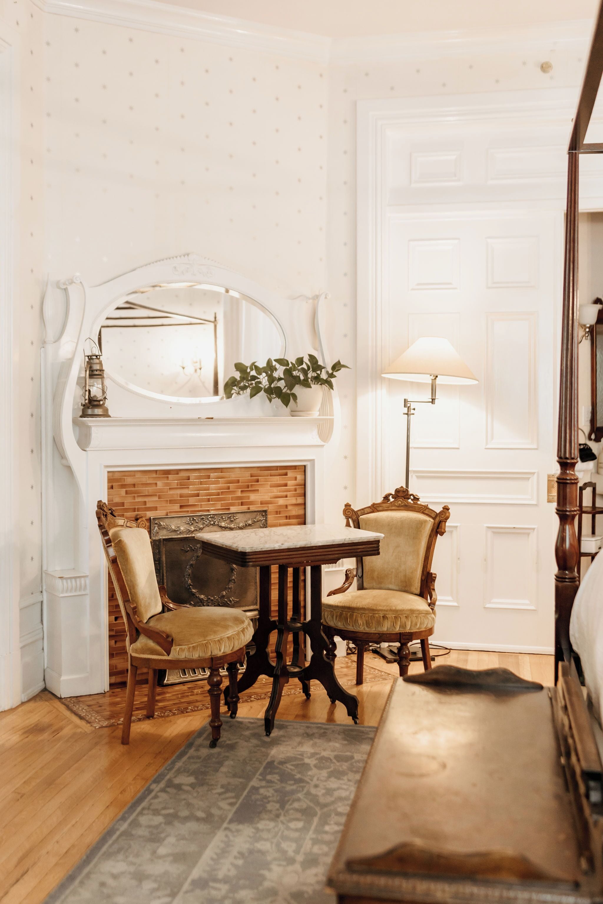 A room with a fireplace, a table with chairs, a lamp, and a mirror.