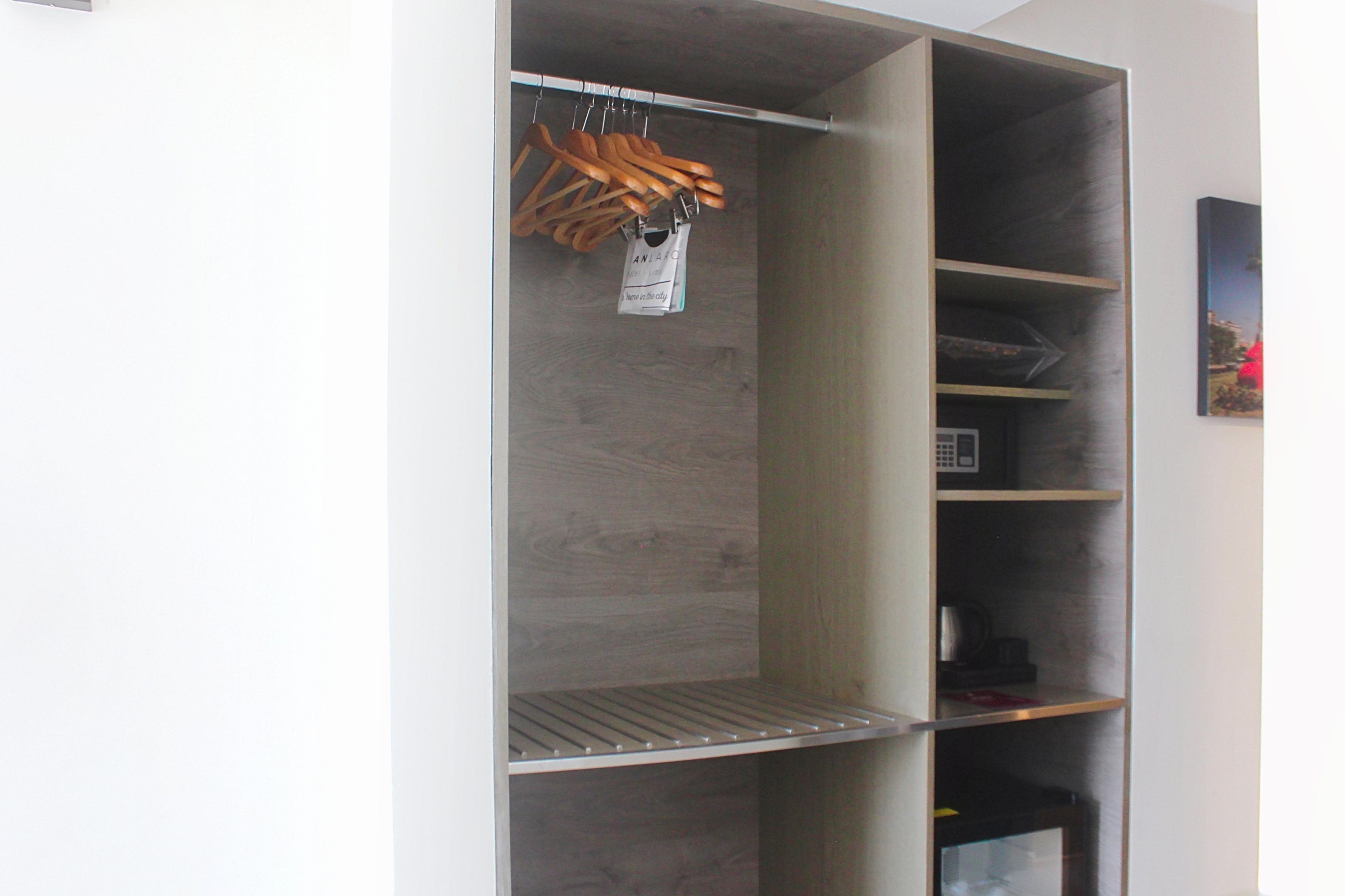 A wardrobe with multiple shelves and hanging space, a metal shelf, and a hanging bag with text.