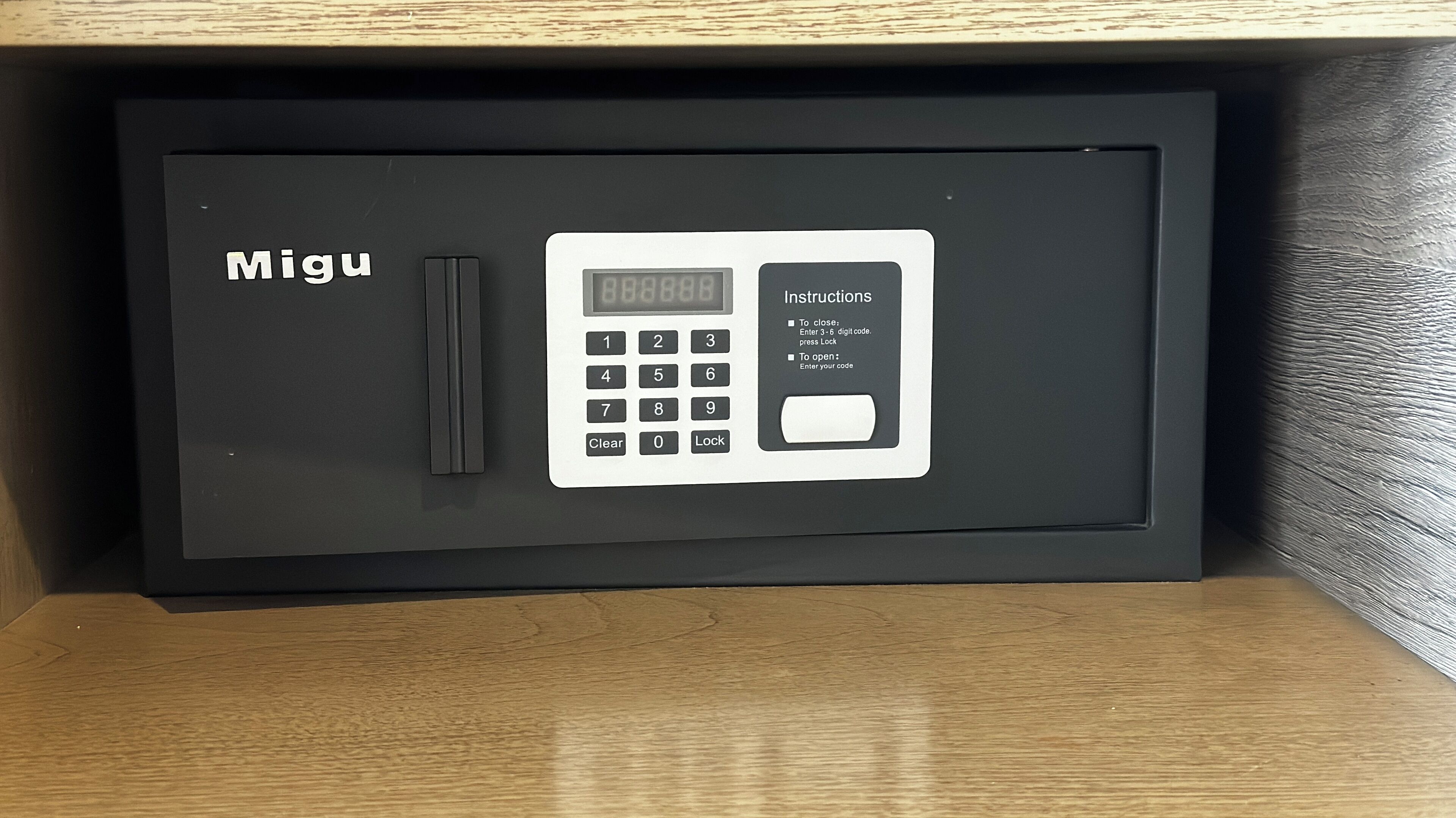 A black safe with a keypad and instructions for entering a code.