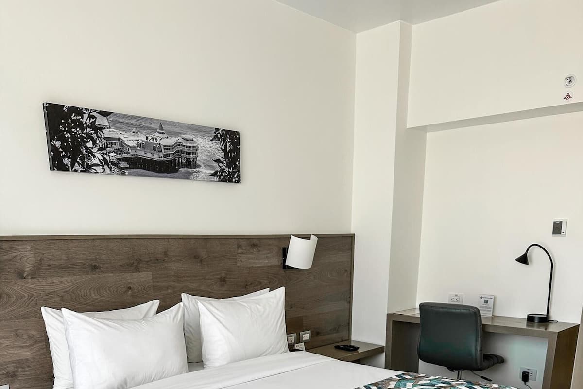 Quarto de hotel com uma cama grande, uma mesa e uma cadeira.