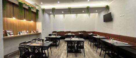 A conference room with tables and chairs, wooden flooring, and hanging plants.