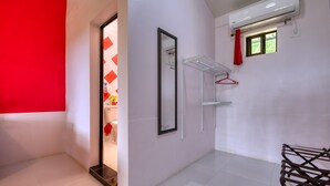 A modern hotel room with a red accent wall, a large mirror, a window with a view, and a metal drying rack. - Casa Conley del Mar (Cahuita)