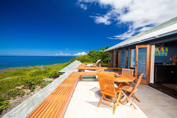 A patio with wooden furniture overlooking a scenic ocean view. - Sea Lodge 2 People (Roatan)