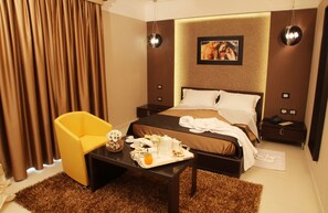 A hotel room with a bed, a bedside table with a tray of breakfast items, a yellow armchair, and a large window with curtains. - Hotel Cenacolo (Somma Vesuviana)
