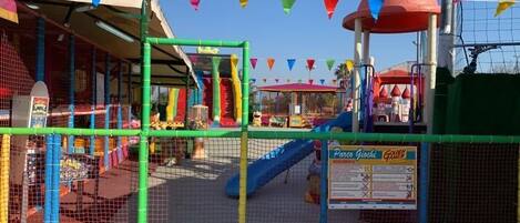 A playground with slides and climbing structures, surrounded by a safety net.