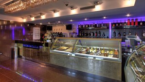 Zona de bar moderna con una vitrina de postres, una selección de botellas de licor y un candelabro.