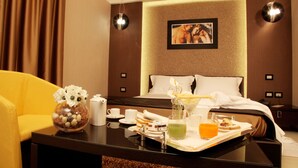 Una habitación de hotel con una cama, una mesita de noche con un jarrón de flores, una bandeja con alimentos para el desayuno y un cuadro en la pared.
