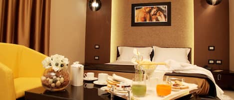 A hotel room with a bed, a bedside table with a vase of flowers, a tray with breakfast items, and a picture on the wall.