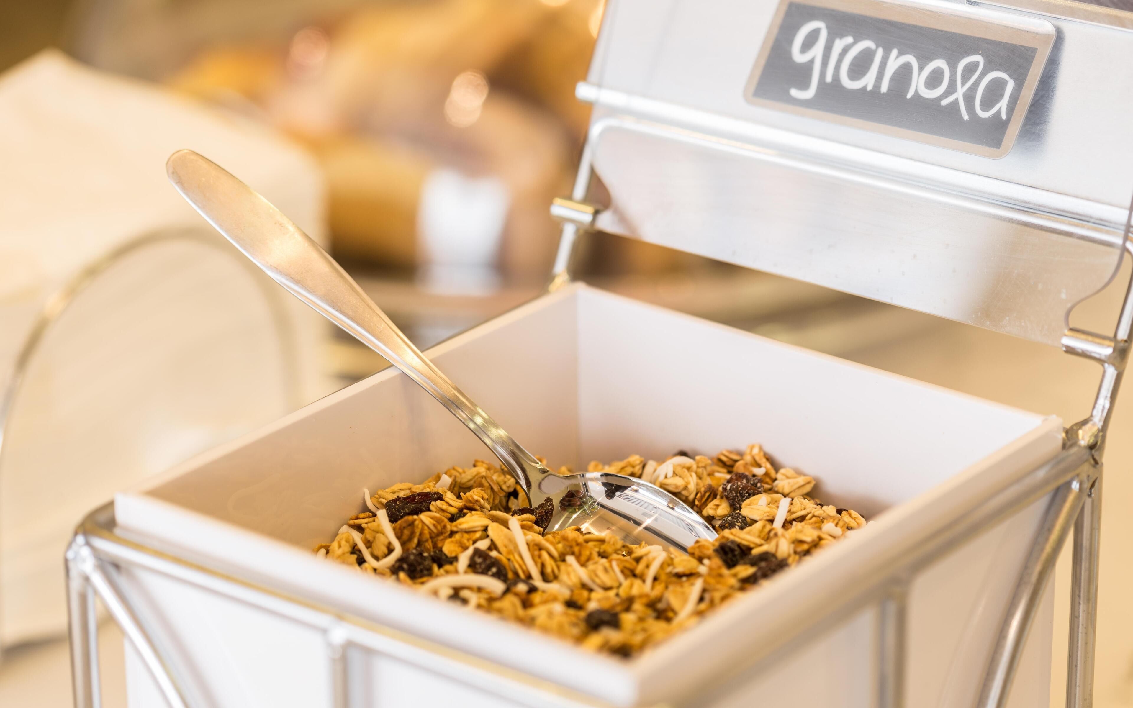 A granola container with a spoon inside, placed on a table.