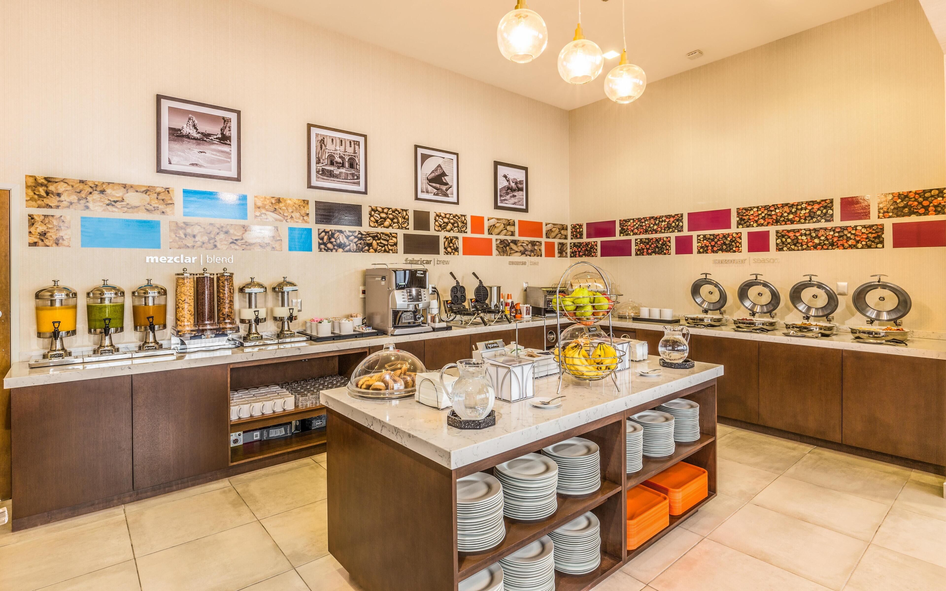 Un bufé de desayuno con distintas estaciones de comida, máquinas de café y una barra de café.