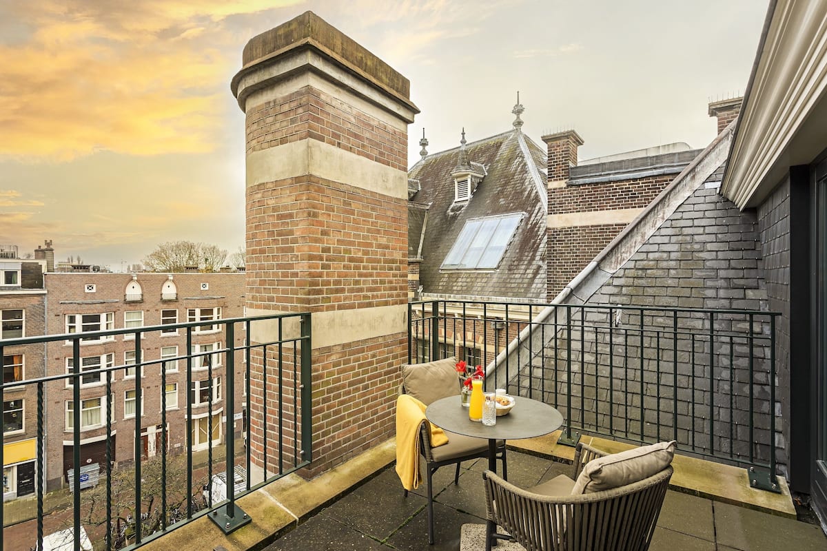 A balcony with a table, chairs, and a brick wall.