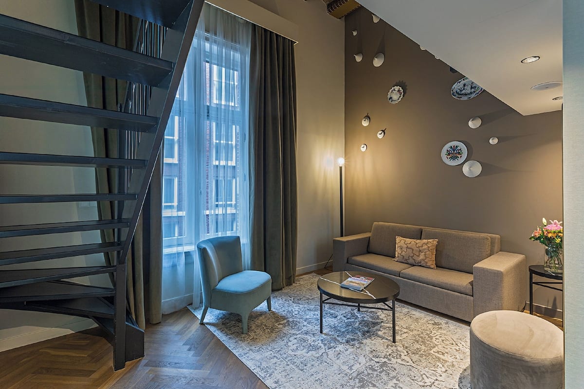 A modern living room with a sofa, a chair, a coffee table, and a staircase.
