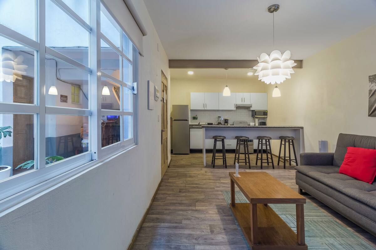 Une cuisine moderne avec des meubles blancs, un îlot central et des tabourets de bar.