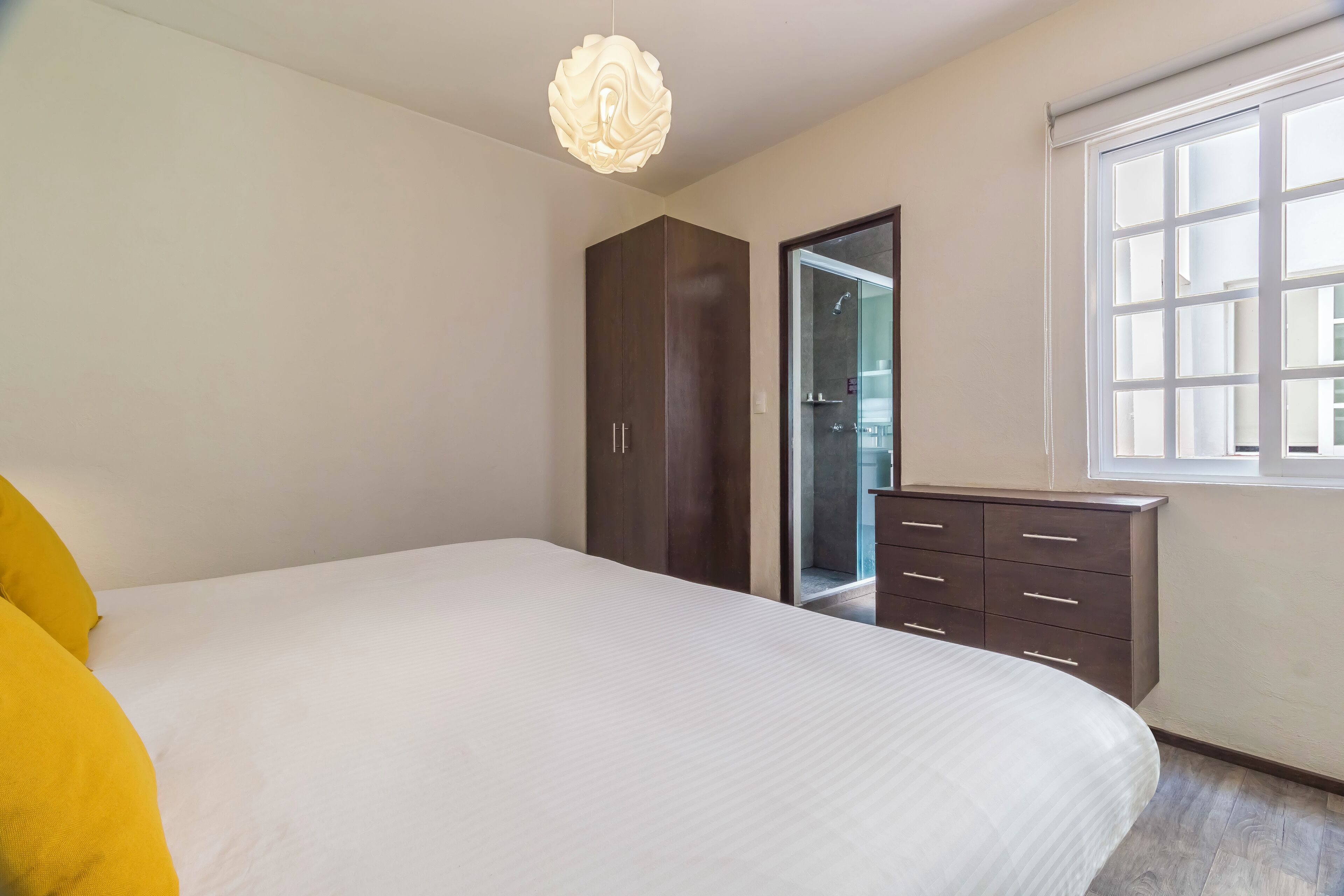 Une chambre à coucher avec un grand lit, une armoire, une commode et une fenêtre.