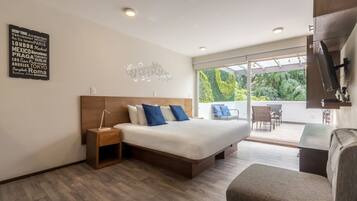 Une chambre moderne avec un grand lit, une table de chevet, une chaise et une vue sur l’extérieur grâce à une porte vitrée.