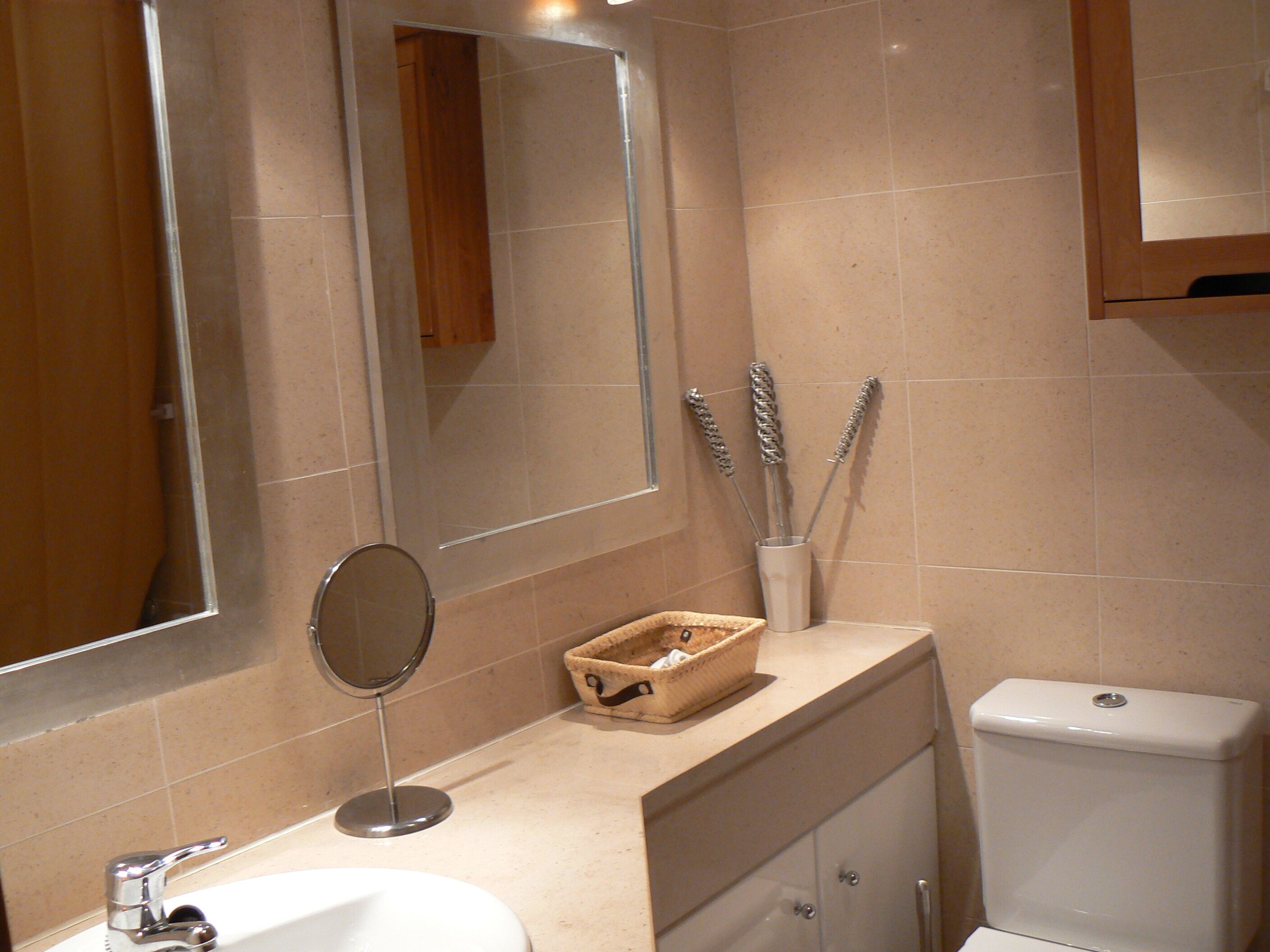 A bathroom with a sink, mirror, toiletries, and a toilet.